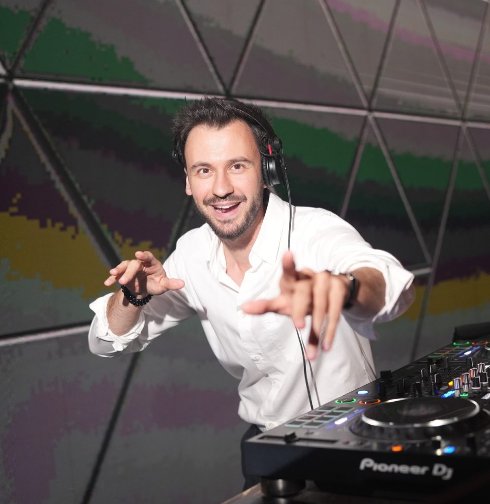 Laughing DJ Bury in a white shirt behind Pioneer decks entertaining guests – DJ for corporate parties in Ostrava