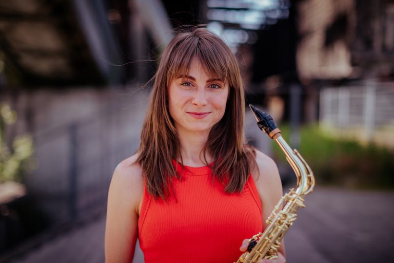 Saxophonist Nikisaxi with her saxophone in an industrial setting – saxophonist for corporate events in Prague