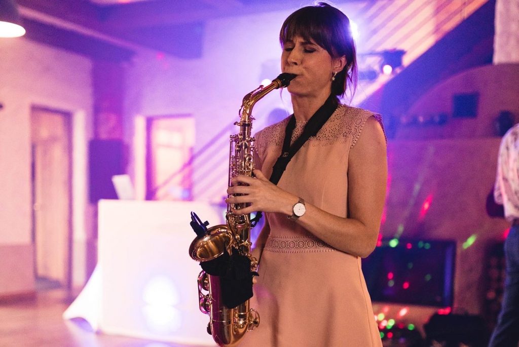 Saxophonist Nikisaxi playing in a purple-lit hall at a wedding party
