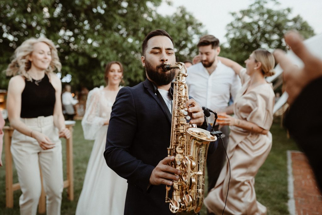 Saxophonist Johny Sax playing among dancing guests at a wedding at Fara Brixi