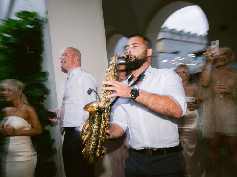 Saxophonist Johny Sax playing among guests at a social party