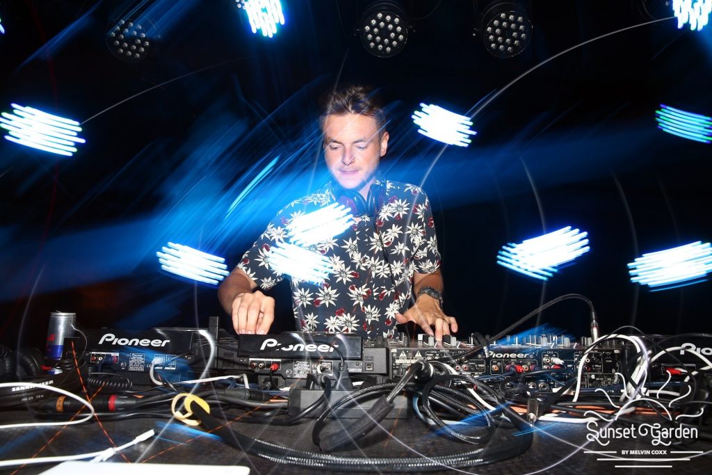 DJ Václav Brom playing behind the decks in a light show at a corporate party