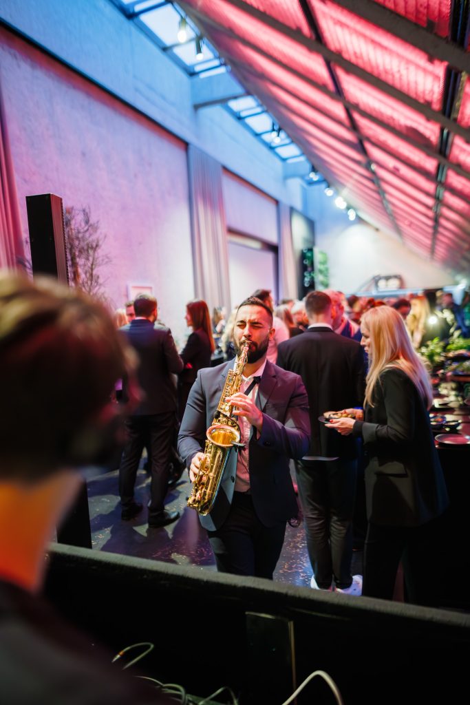 Saxophonist Johny Sax walking among guests at a corporate party – saxophonist for events in Ostrava