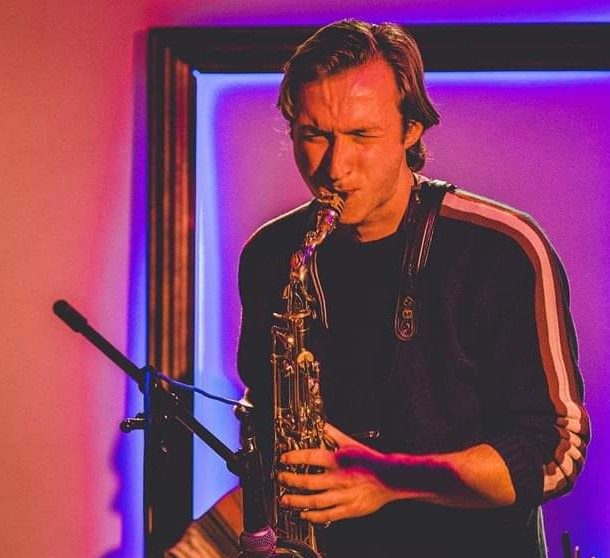 Saxophonist Kryštof Janáček playing in a purple-lit club at a corporate event