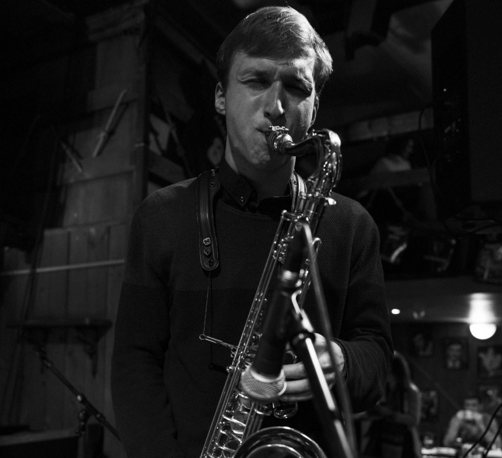 Black-and-white photo of saxophonist Kryštof Janáček playing at a corporate party – saxophonist for events in Brno – Kryštof Janáček