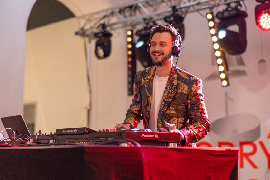 DJ Bury ve vzorovaném saku hraje na firemní párty s pódiovými světly