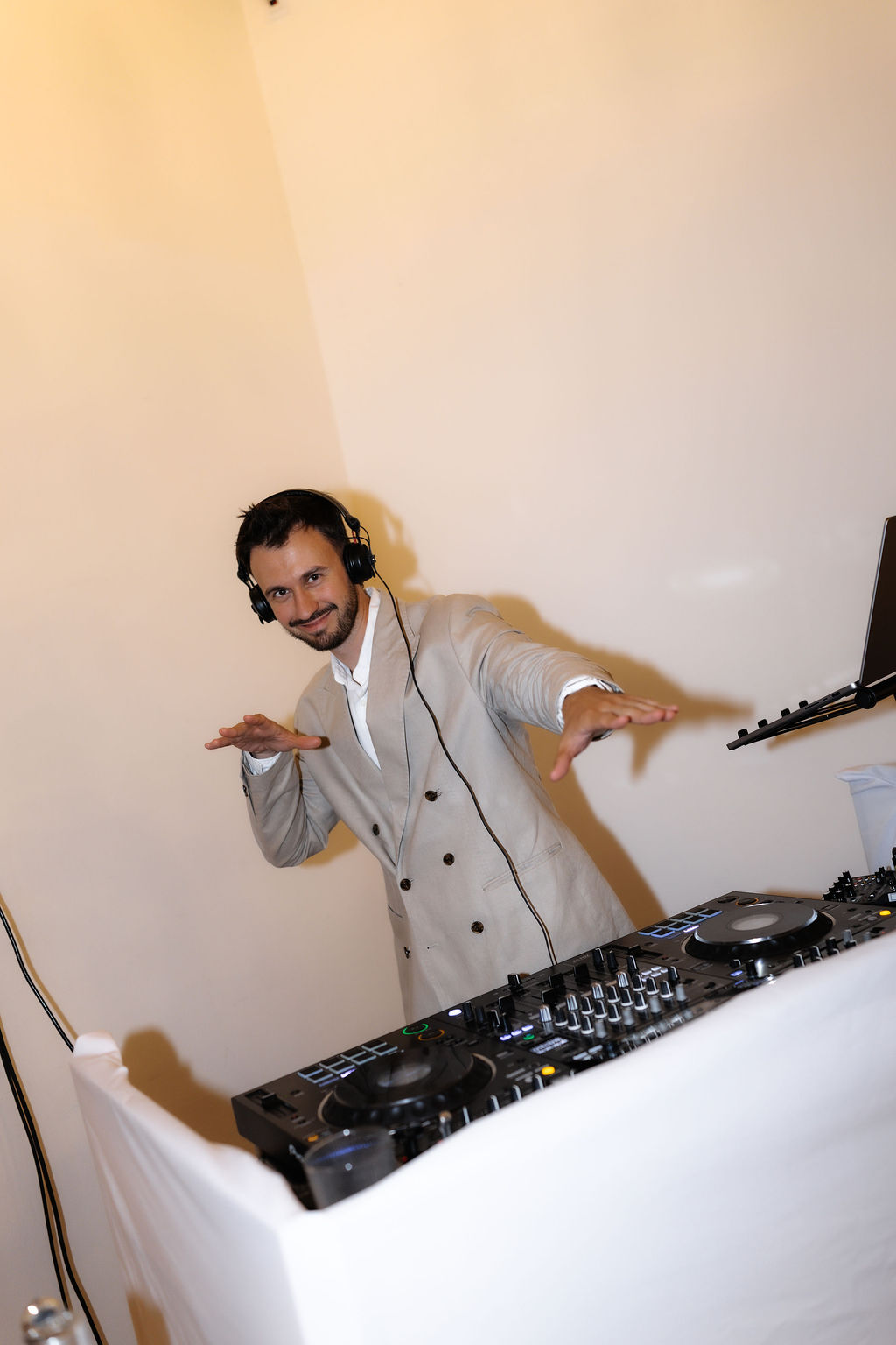 DJ v béžovém obleku hraje za DJ pultem na svatbě v Mlýně u Vodníka Slámy
