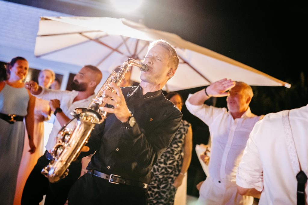 Saxofonista DeeSaxx hraje živě mezi hosty na venkovní akci