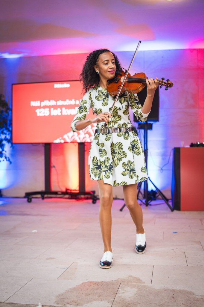 Violinist Iska.muse playing in front of a screen celebrating Miele’s 125 years