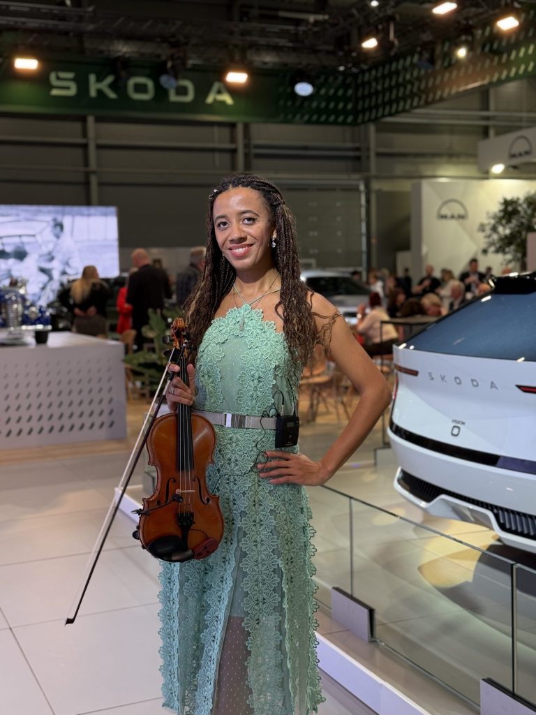 Houslistka Iska.muse s houslemi na stánku Škoda Auto na výstavě e-SALON 2025 v PVA Expo Praha