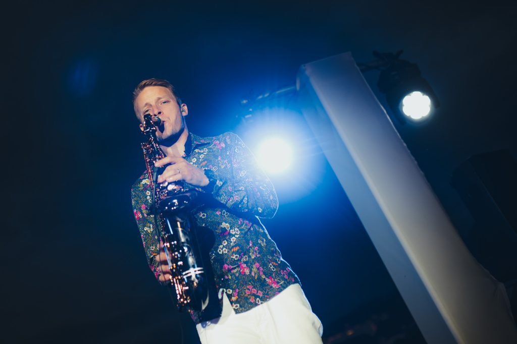 Saxofonista DeeSaxx hraje v modrých světlech na party Accolade, KVIFF 2022